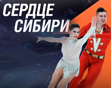 Фигуристы в ярких костюмах исполняют парное катание на фоне надписи Сердце Сибири. Один в белом наряде, другой в красном. Обстановка создает настроение движения и динамики